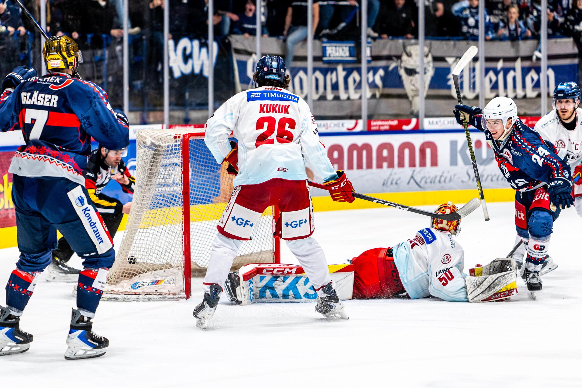 Gleich passiert es: Nachdem Paul Vinzens (rechts, blaues Trikot) in dieser Szene nach seinem Treffer zum Jubeln fahren will, verpasst ihm Moritz Kukuk (Mitte, weißes Trikot) einen Check mit dem Schläger ins Gesicht.  (Bild: Elke Englmaier)