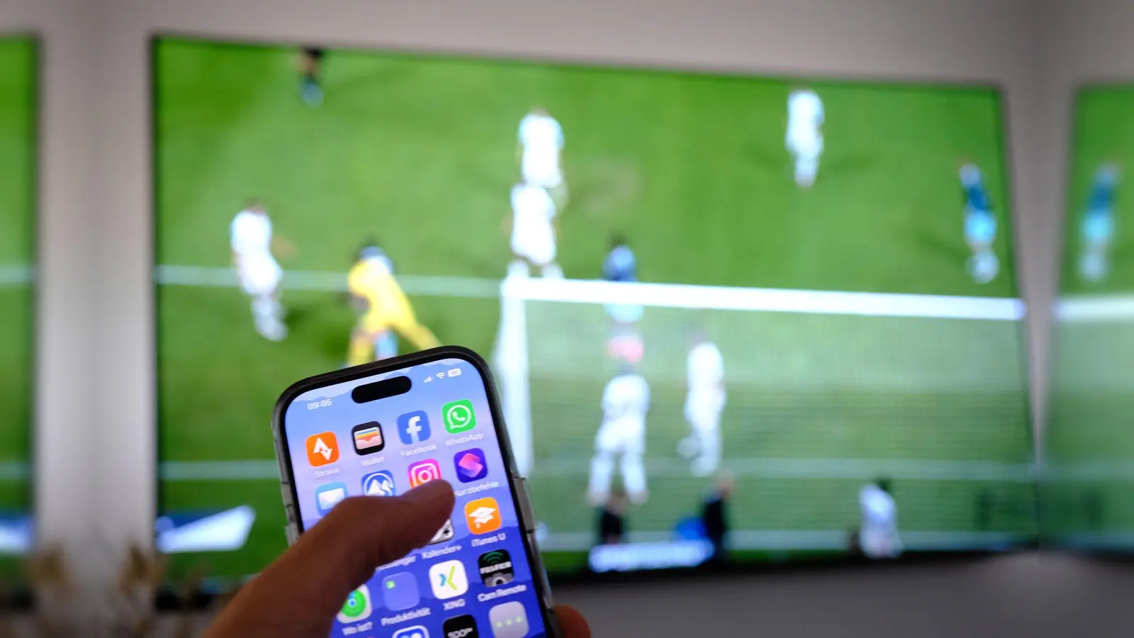 Nebenbei mal daddeln: Während das Fußballspiel läuft, schauen viele Zuschauer nebenbei aufs Handy. (Symbolbild: Bernd Weißbrod/dpa)