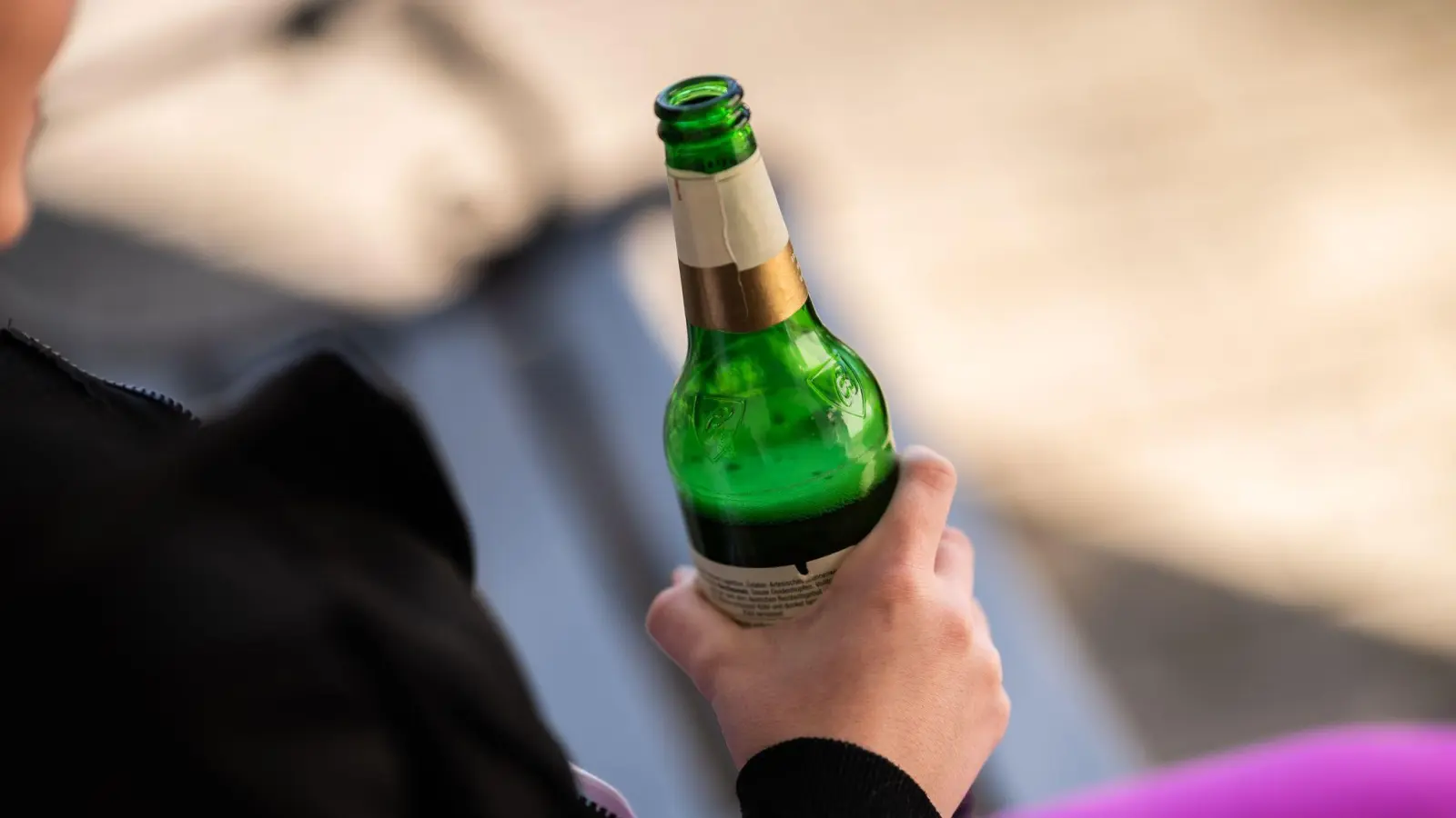 Eine Jugendliche hält vor ihrem Haus eine Flasche Bier in der Hand. (Bild: Silas Stein/dpa/Symbolbild)