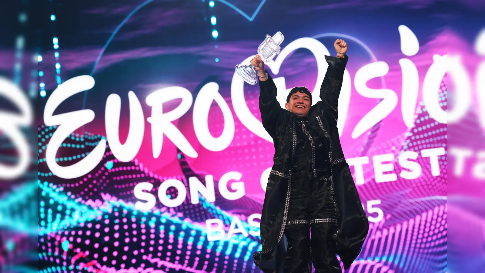 JJ aus Österreich, Gewinner des Eurovision Song Contest, hält während des großen Finales des 69. Eurovision Song Contest auf der Bühne die Trophäe in der Hand und jubelt (Bild: Jens Büttner/dpa)