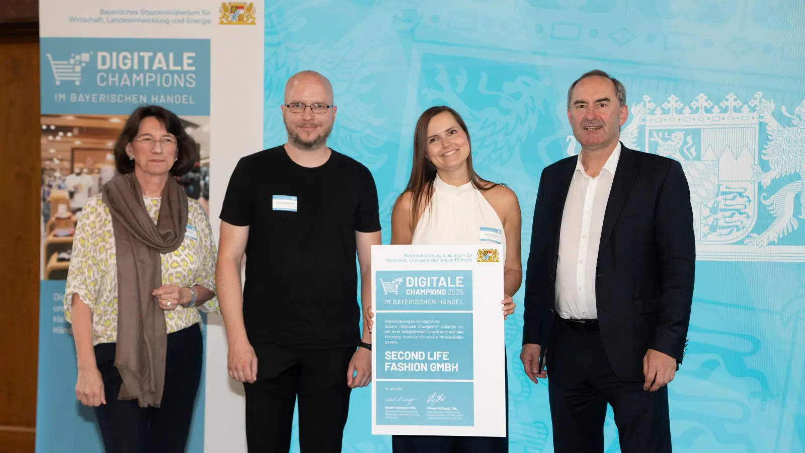 Lisa Samhammers (zweite von rechts) Unternehmen Second Life Fashion GmbH wurde beim Wettbewerb „Digitale Champions im bayerischen Handel 2026“ ausgezeichnet. Bayerns Wirtschaftsminister Huber Aiwanger (rechts) übergab die Urkunde an die Preisträgerinnen und Preisträger. (Bild: Wirtschaftsministerium/Bastian Brummer)